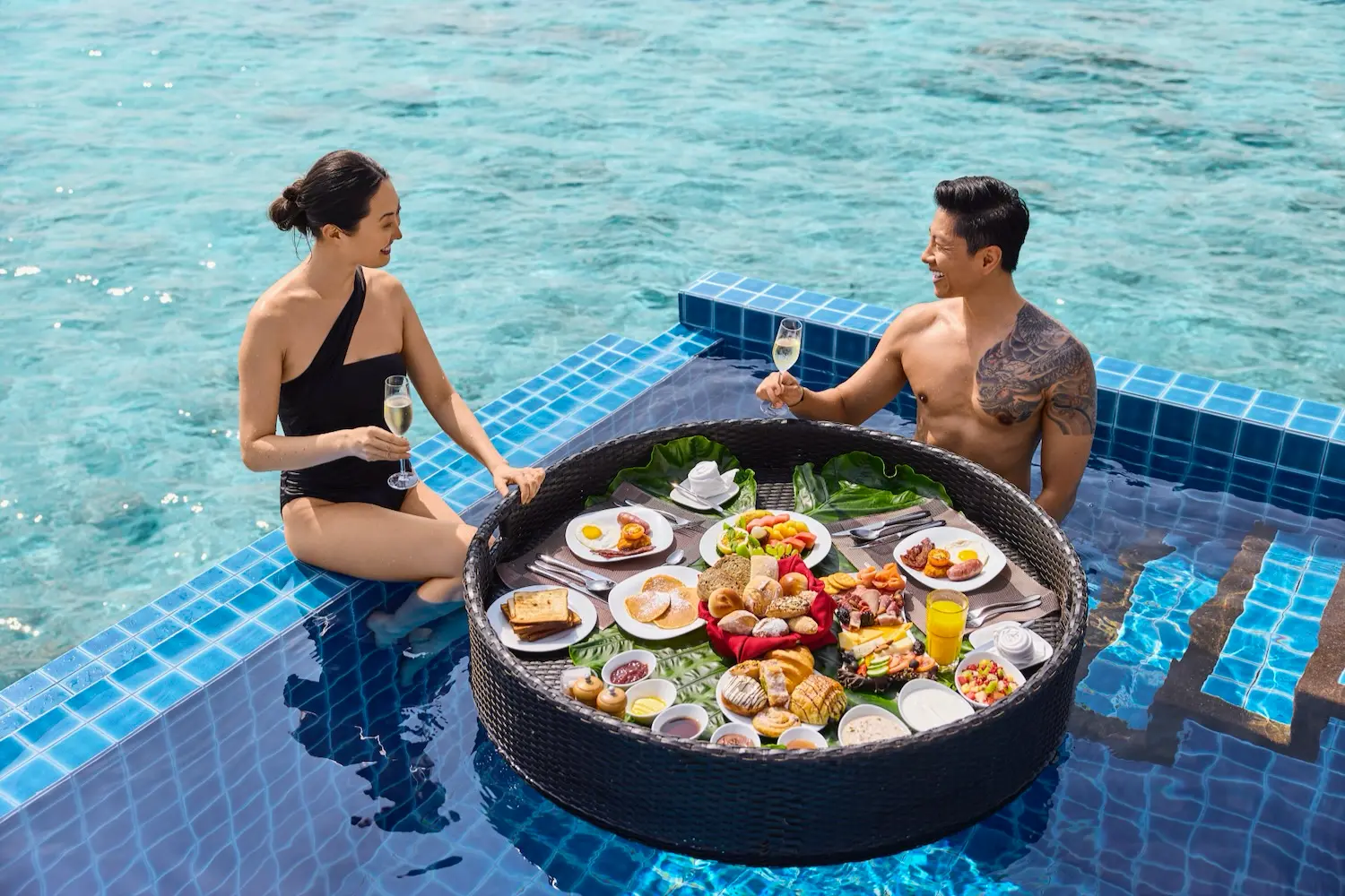 Paar frühstückt im Pool an einem schwimmenden Tablett