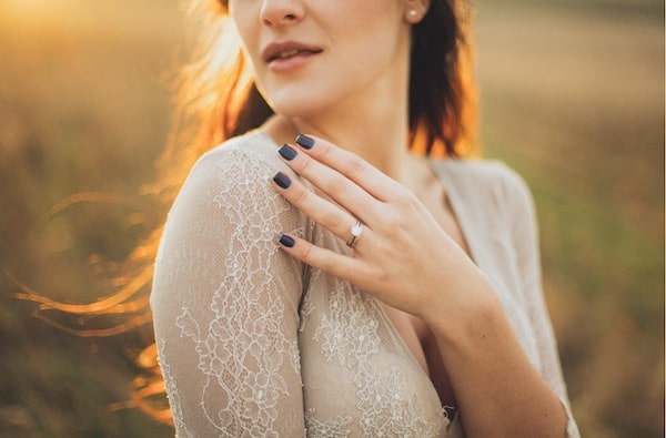 Hand mit Verlobungsring auf der Brust einer Frau