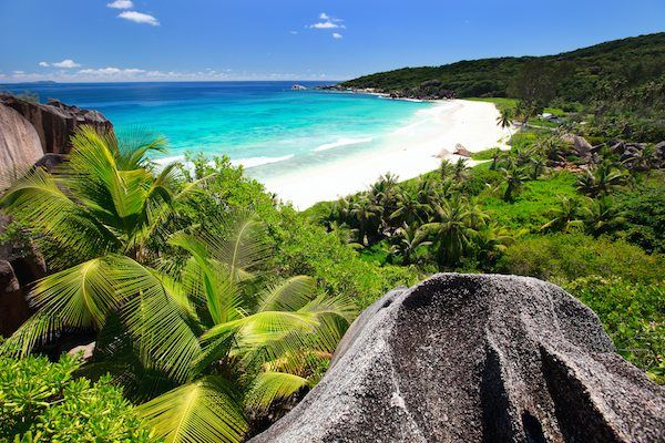 Tropischer Strand mit Palmen und Granitfelsen