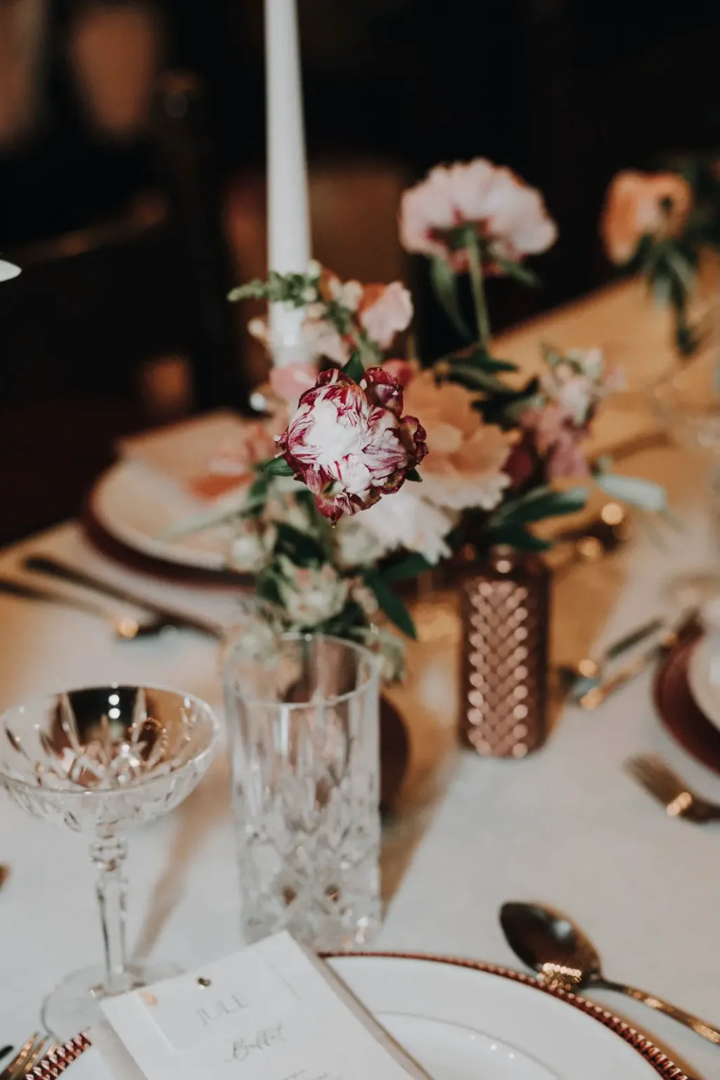 Blumengesteck mit rosa Blüten auf einer gedeckten Tafel