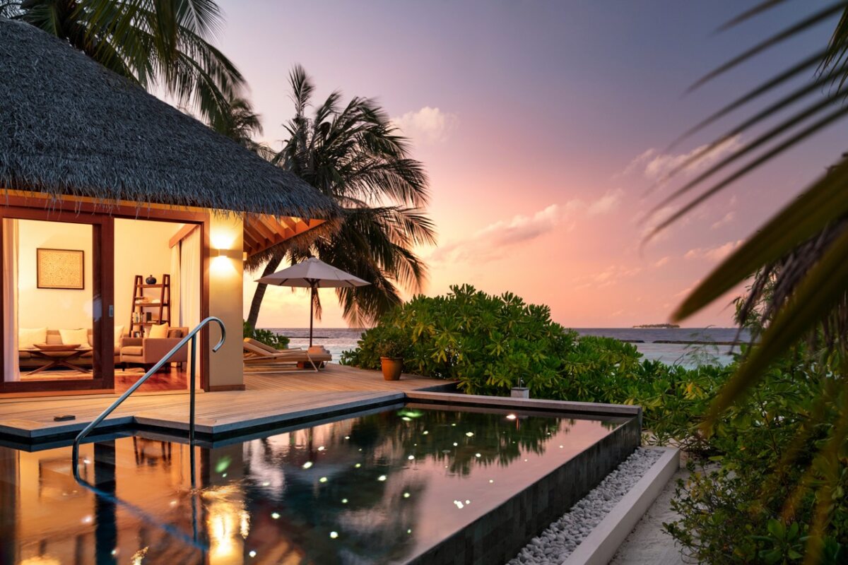 Privater Pool vor einer tropischen Villa bei Sonnenuntergang