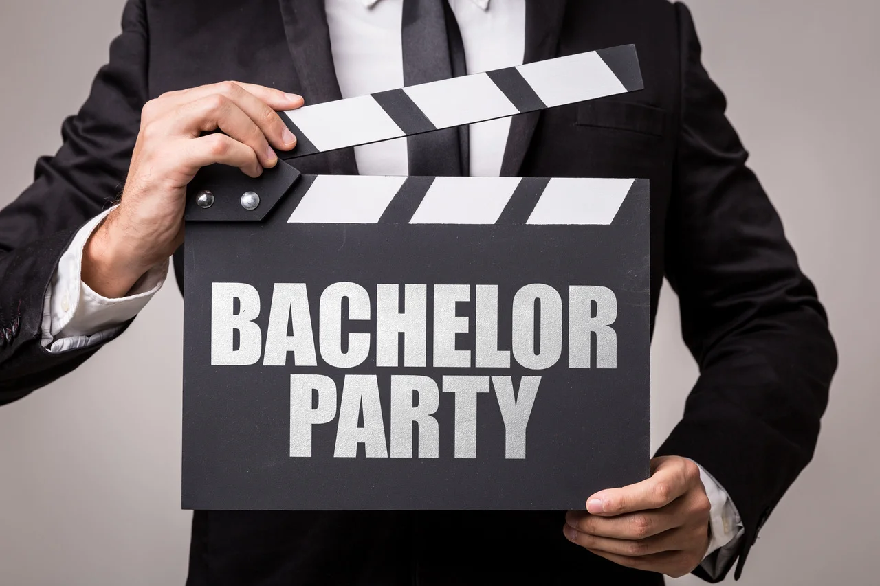 Hochzeitsanzug finden: Bräutigam hält Tafel mit der Aufschrift "Bachelor Party!