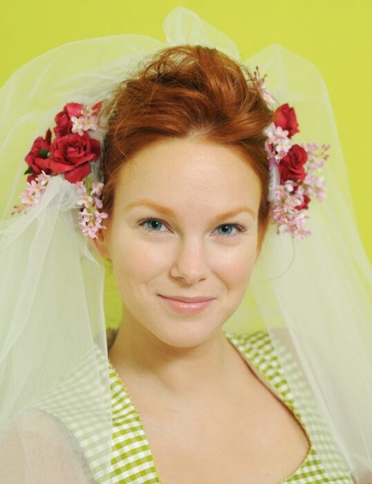 Rothaarige Braut mit Blumen im Haar und Schleier