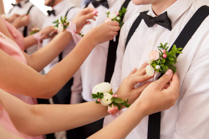 Männliche Brautjungfern bekommen Blumen angesteckt