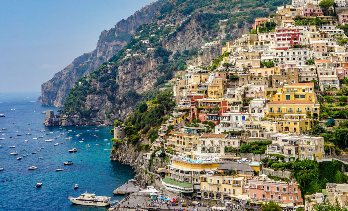 Ein Panoramablick auf die malerische Stadtlandschaft an den Klippen in Kampanien, Italien, mit farbenfrohen Gebäuden und einem klaren blauen Meer.