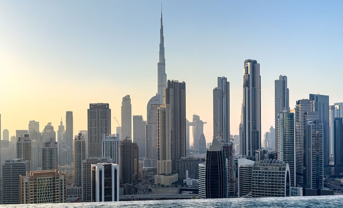 Honeymoon Horoskop: Die Skyline von Dubai zeigt den Burj Khalifa, Hochhäuser und moderne Architektur im Hintergrund. Die Szene wird von einem Infinity-Pool auf einem Wolkenkratzer aus beobachtet, während das goldene Stundenlicht die Stadt erleuchtet.