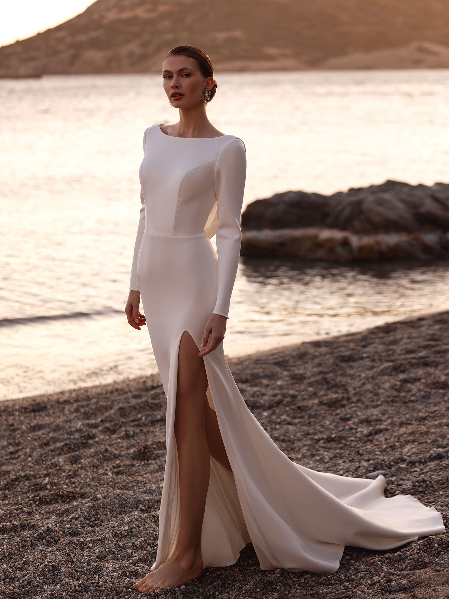 Brautkleid aus Crepe mit Bateau-Ausschnitt, langen Ärmeln und Beinschlitz von Destination Romance. Model DR422.