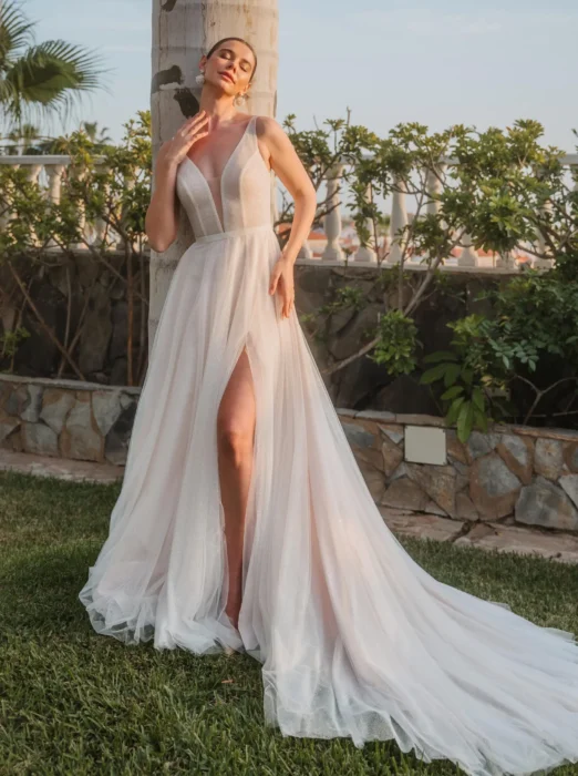 Braut in fließendem ärmellosem Kleid mit Beinschlitz im Garten