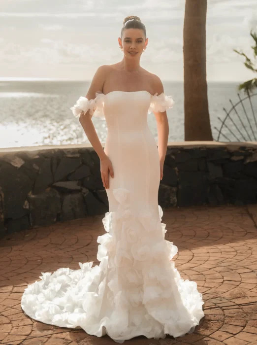 Braut in schulterfreiem figurbetontem Kleid mit Rüschenrock am Meer