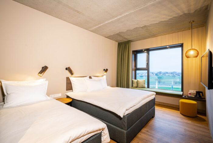 Hotelzimmer mit zwei Betten und Blick in die Landschaft
