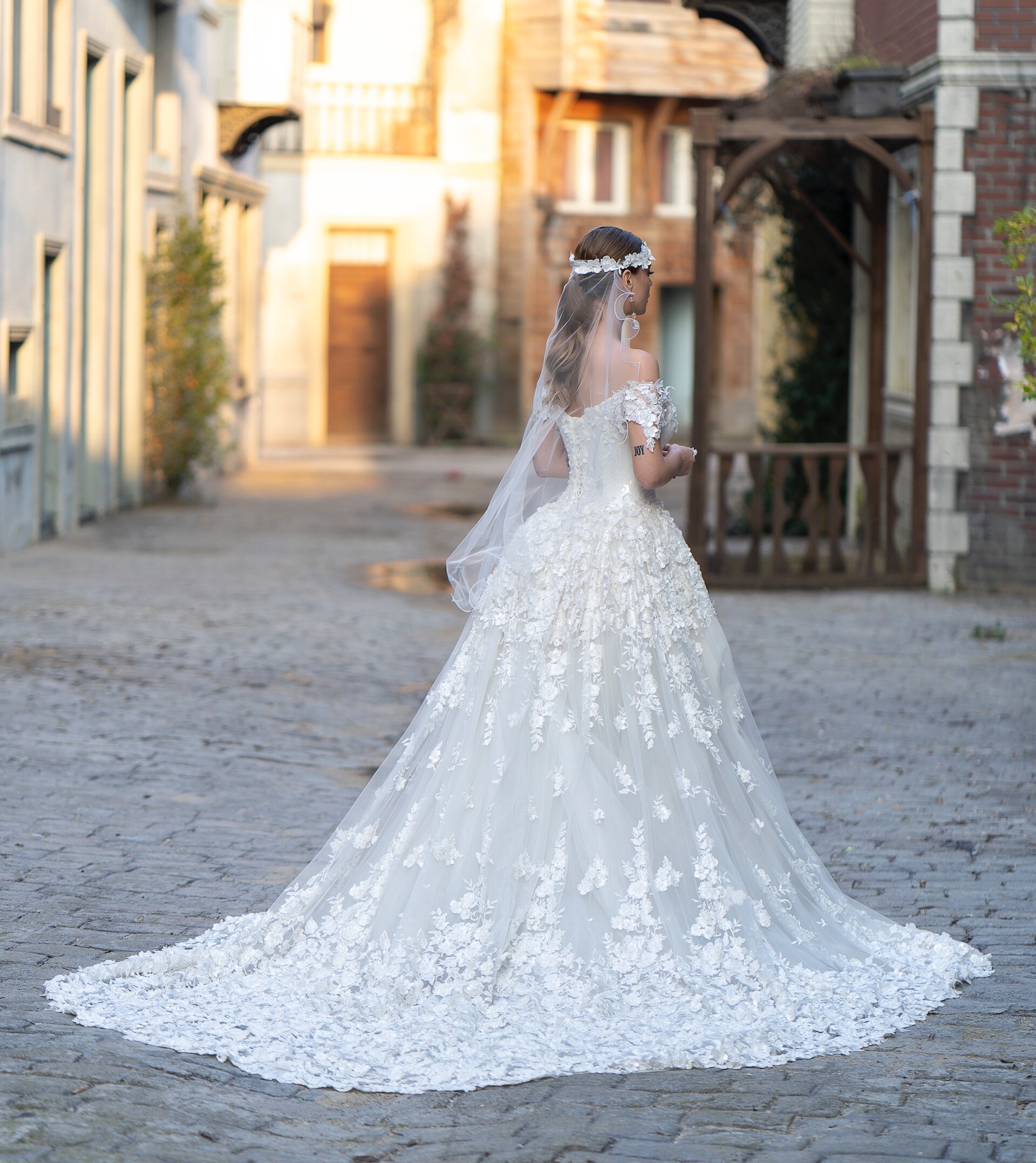 Extravagantes Brautkleid im Fit-and-Flare-Schnitt mit üppiger Schleppe, Carmen-Ausschnitt und Blüten-Applikationen von Emine Yildirim, Modell 9005
