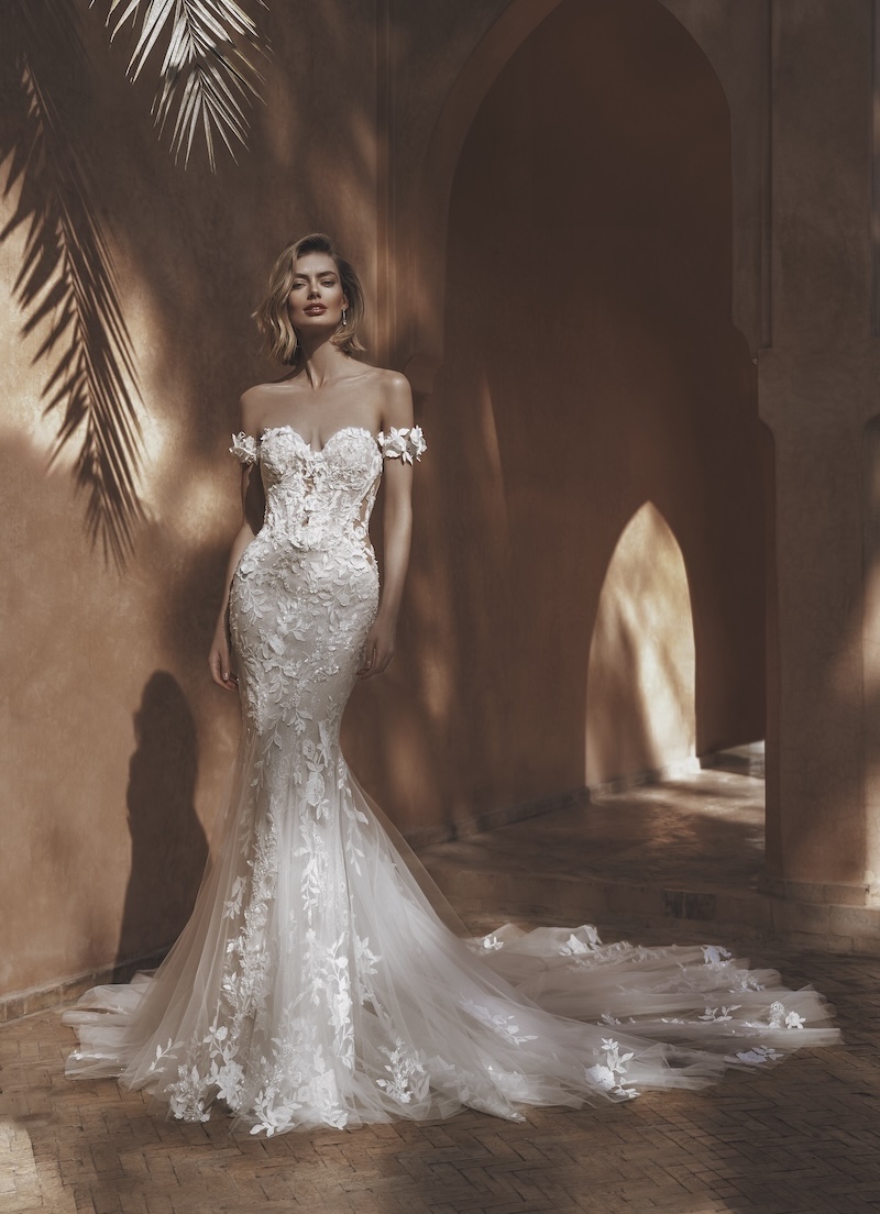 Brautkleid im Fit-and-Flare-Schnitt aus bestickter blumiger Spitze mit herzförmigem Ausschnitt, abnehmbaren Offshoulder-Trägern, seitlichen transparent unterlegten Cut-outs und Schleppe von Enzoani, Modell Unity