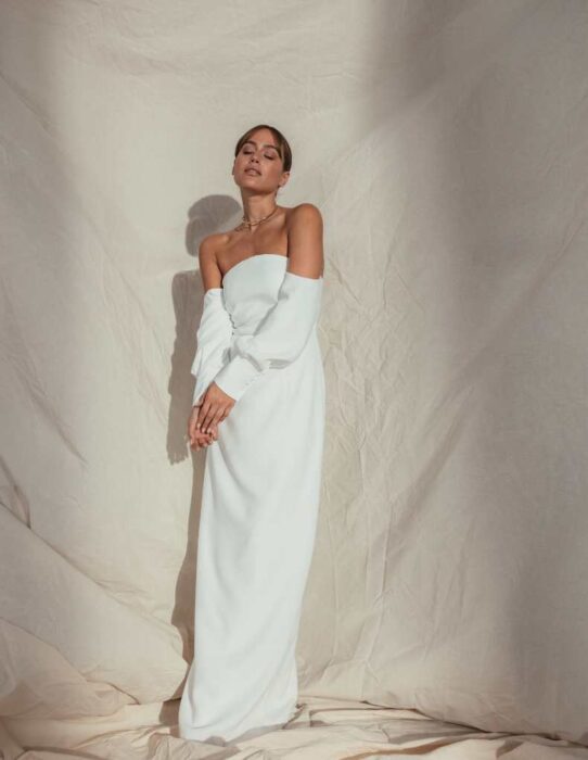 Puristisches, schulterfreies Hochzeitskleid aus Crêpe in I-Linie mit Bandeau-Ausschnitt und Carmen-Ärmeln von IamYours, Modell Arista