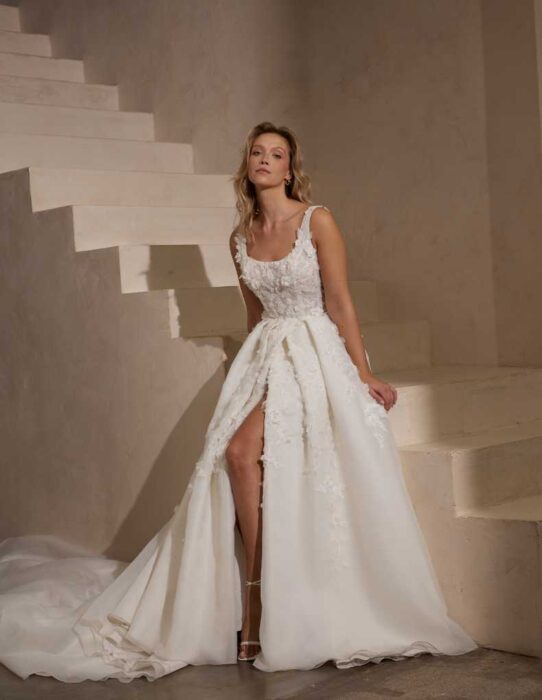 Elegantes Brautkleid im Prinzessstil mit 3D-Blüten und transparent unterlegten Cut-outs, langer Schleppe und Beinschlitz, Dekolleté in Karrée-Form und tiefem Rücken sowie langen Ärmeln von IamYours, Modell Novelie