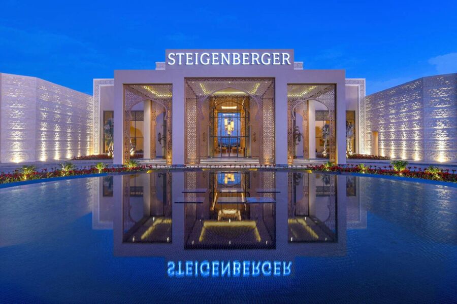 Beleuchteter Hoteleingang mit Spiegelung im Wasser