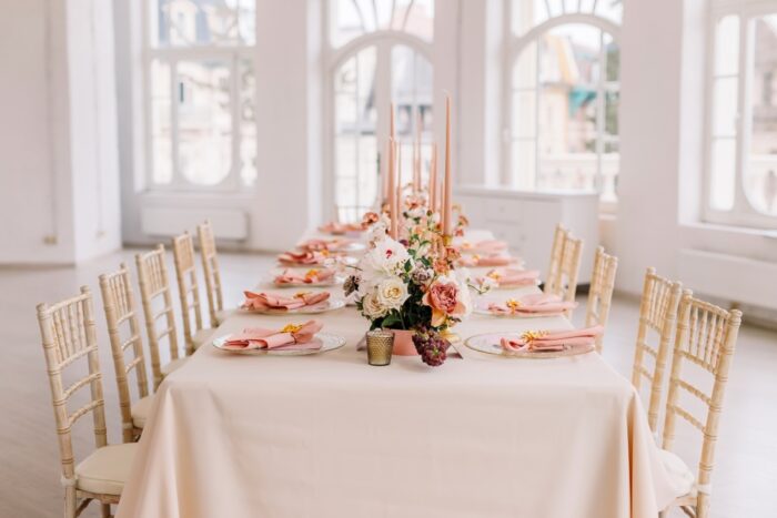 Hochzeitsdekoration im Saal: Blumengesteck im Vintage-Stil.Festlich gedeckter Tisch in Pfirsich-Rosa und Pastelltönen, geschmückt mit Blumen für Gäste und das Brautpaar.Wunderschöne Tischgestaltung.