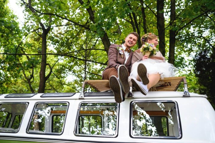 Junges, schönes Brautpaar sitzt auf einem grünen Minivan