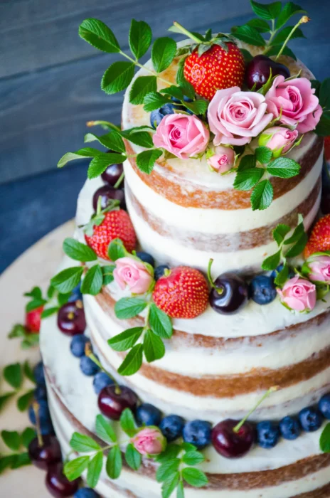 Mehrstöckige Hochzeitstorte mit Beeren und grünen Blättern
