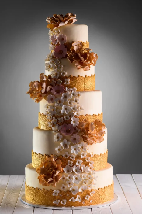 Hohe mehrstöckige Hochzeitstorte mit goldfarbenen Blüten
