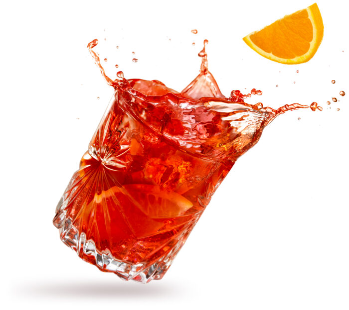 Negroni mit Eis und Orangenscheibe vor weißem Hintergrund