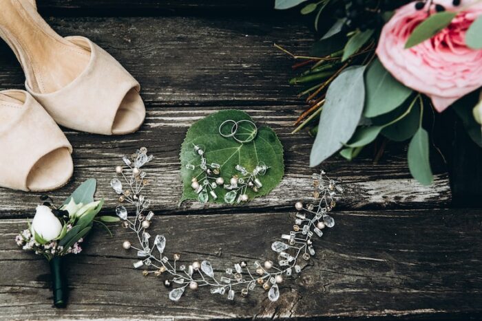 Brautschmuck mit floralen Details, Ringen, Schuhen und Blumen auf Holz